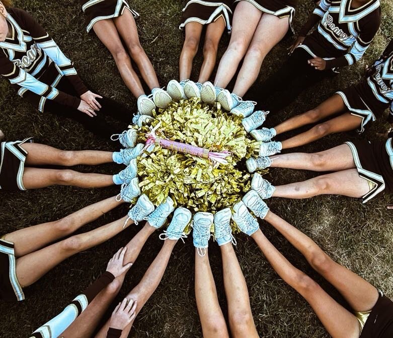 Stonington Bears cheerleaders' gold poms and sneakers arranged together in a circle on the field