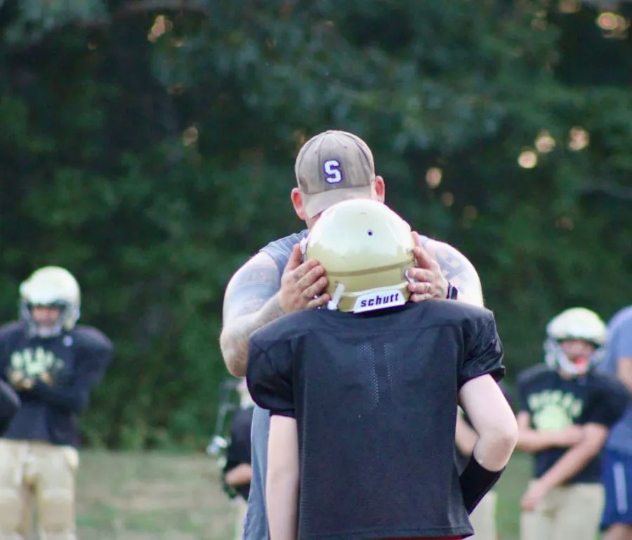 Coach fitting a Bears player's helmet at practice